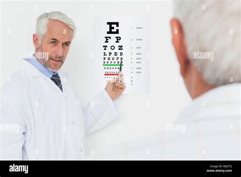 Male Pediatrician Ophthalmologist With Senior Patient Pointing At Eye