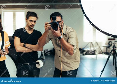Photographer With His Team Doing A Photo Shoot In A Studio