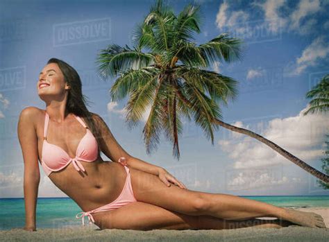 Caucasian Woman In Pink Bikini Near Palm Tree At Beach Stock Photo