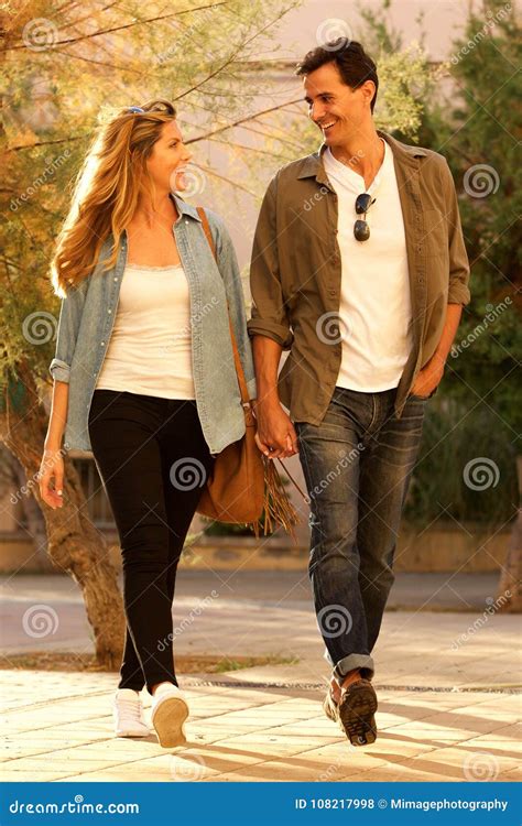 Full Length Happy Couple Walking Together And Holding Hands Stock Photo