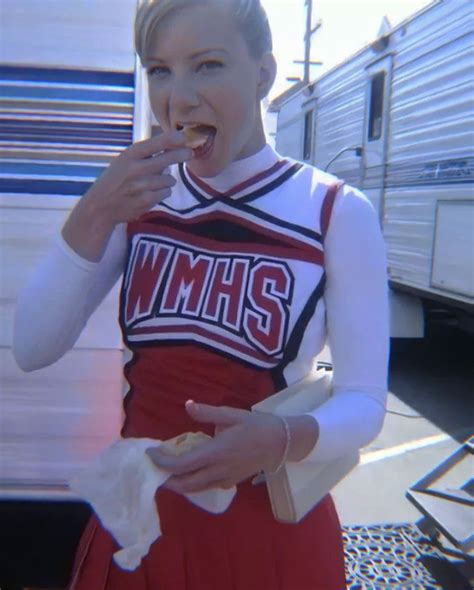 A Woman In A Cheerleader Uniform Eating Food From A Napkin While