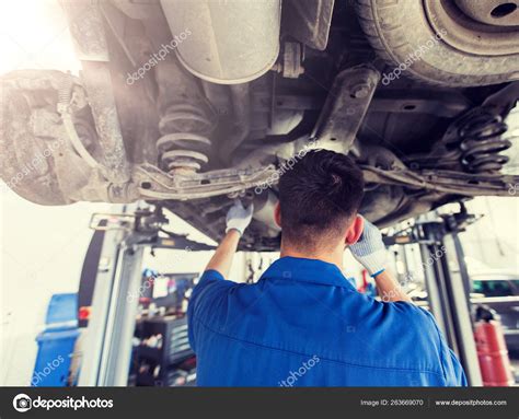 Mechanic Man Or Smith Repairing Car At Workshop Stock Photo By ©syda