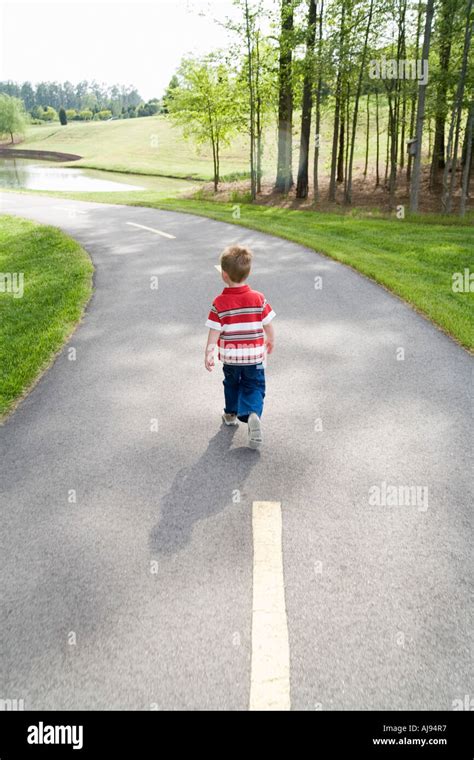 Young Boy Walking Down Path In Park Stock Photo Alamy