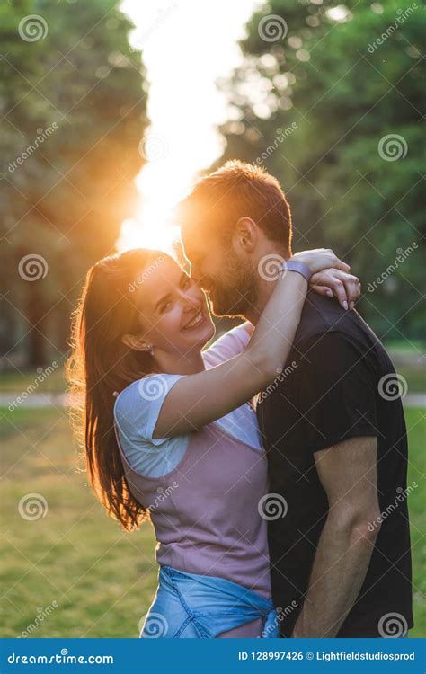 Smiling Young Woman Embracing Boyfriend And Looking At Camera With