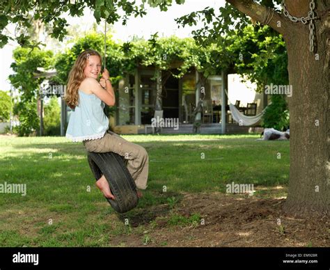 Girl Swinging On Tire Swing In Garden Stock Photo Alamy