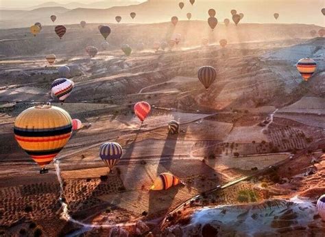 hot air balloons drift over the rocky landscape at cappadocia turkey photo by giulio montini
