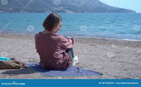 Girl Sits On Beach Soaking Up The Sun S Warmth Blissfully Admires Serene Beauty Of Sea Stock