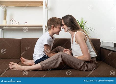 Happy Mom And Son Are Sitting On Couch With Their Foreheads Leaning