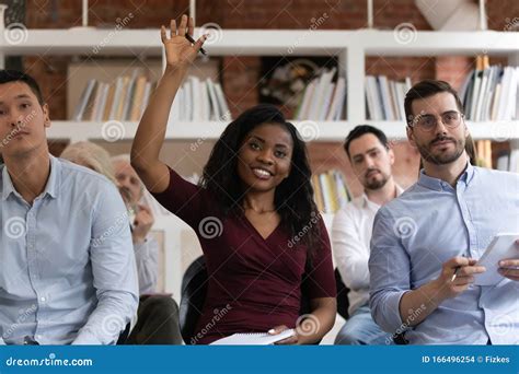 African Woman Raising Hand To Ask Question At Team Training Stock Photo