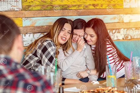 Friends Comforting And Consoling Crying Young Woman Trying To Make Her