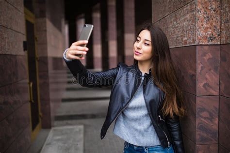 Pretty Young Woman Having Walk And Making Selfie Near Building On