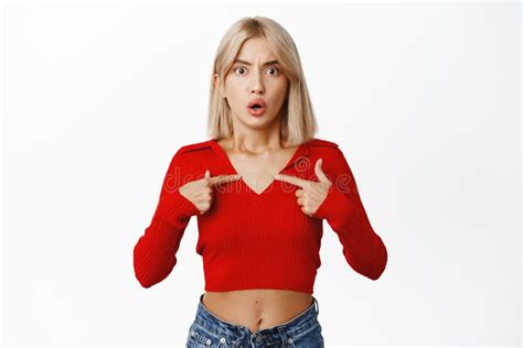 portrait of attractive blond female model in stylish casual clothes pointing fingers at herself