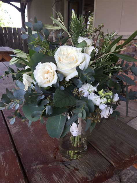 A Vase Filled With White Flowers Sitting On Top Of A Wooden Table