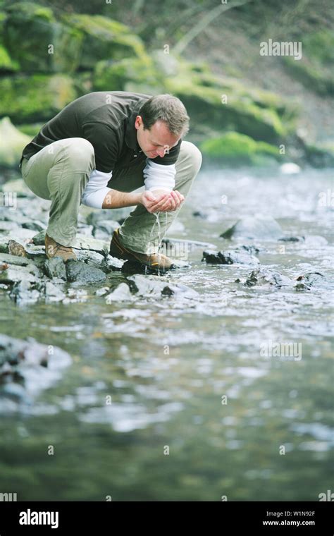 Man Drinking Water From A Stream Stock Photo Alamy