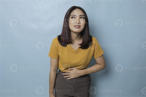 Young Asian woman with arms on stomach and bending over with