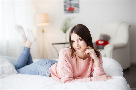 wallpaper model portrait looking at viewer lying on front in bed jeans socks sweater