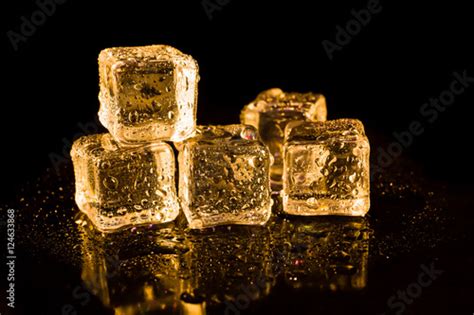 Ice Cubes Of Gold Color On A Reflective Surface Stock Photo Adobe Stock