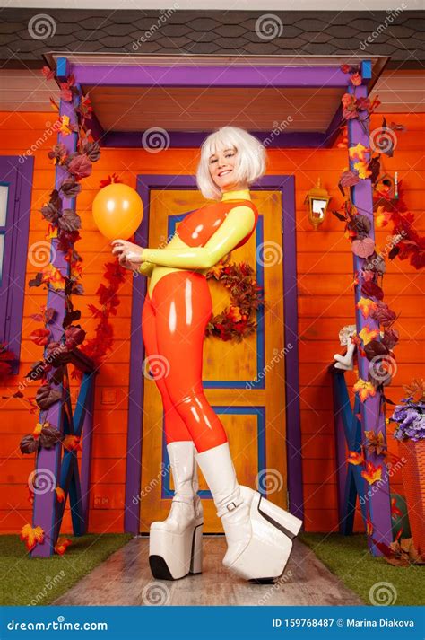 Hot Pretty Blonde Woman In Bright Colorful Latex Rubber Catsuit Ready For Halloween Autumn Party