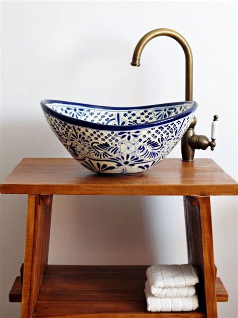 A Bowl Shaped Sink Sitting On Top Of A Wooden Table Next To A Towel Rack