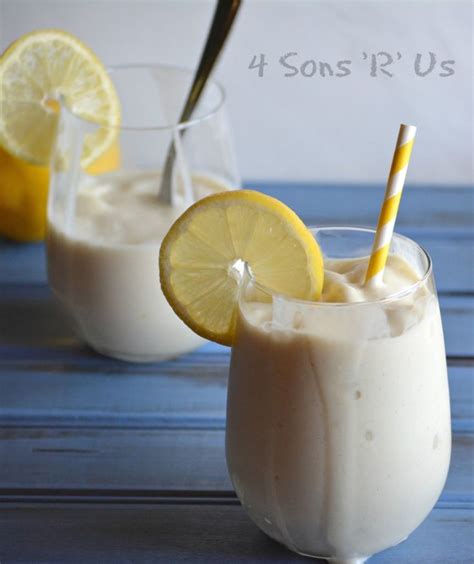 Two Glasses Filled With Milk And Lemons On Top Of A Blue Table Next To