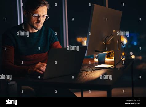Web designer working late in an office, using his laptop to complete a