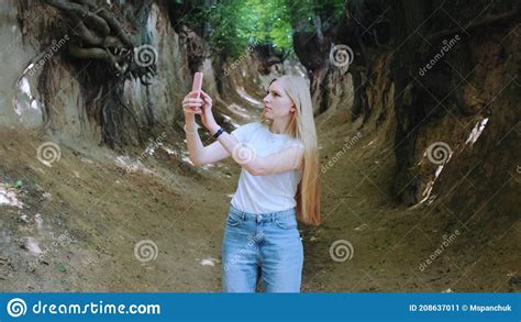 Blonde Young Woman Making Photos On Smartphone In Magical Roots Gorge