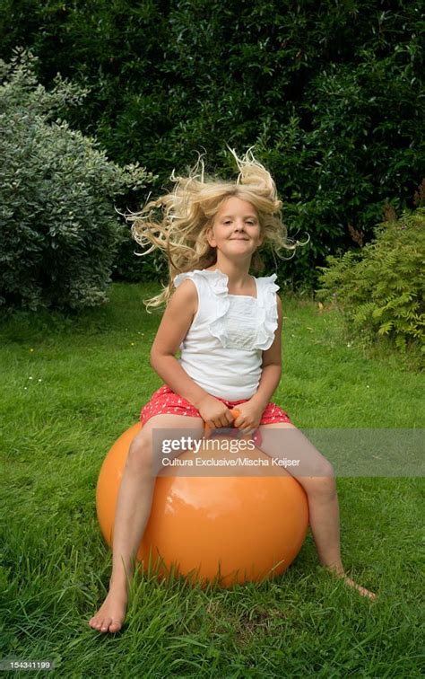 Girl Bouncing On Ball In Meadow Photo Getty Images