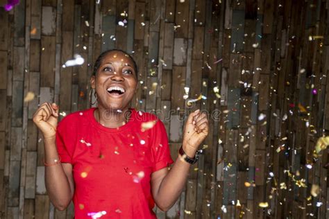 Happy African Female Celebrating With Confetti In Front Of A Wooden