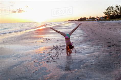 Caucasian Girl Doing Cartwheels On Beach Stock Photo Dissolve