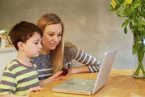 Mid Adult Woman And Son Looking At Laptop On Dining Table Stock Photo Dissolve