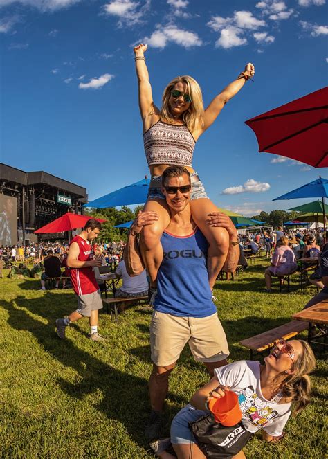 A Man Carrying A Woman On His Shoulders At An Outdoor Music Festival In