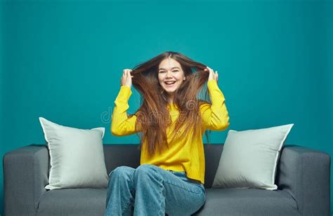 Pretty Young Laughing Girl With Long Hair Having Fun Sitting On Sofa Haircare Cosmetics Ad