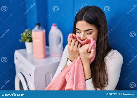 Joven Y Hermosa Mujer Hispana Sonriendo Confiadamente Oliendo Ropa Limpia En La Lavandería Foto