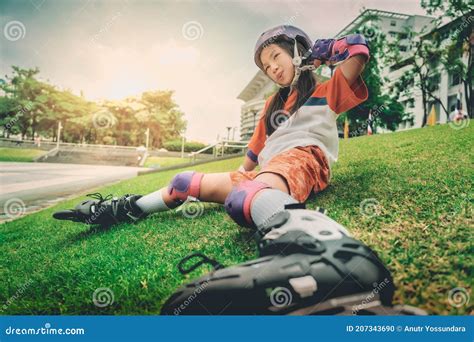 Little Skater Girl Sitting And Relaxing On A Grass Floor After Skating