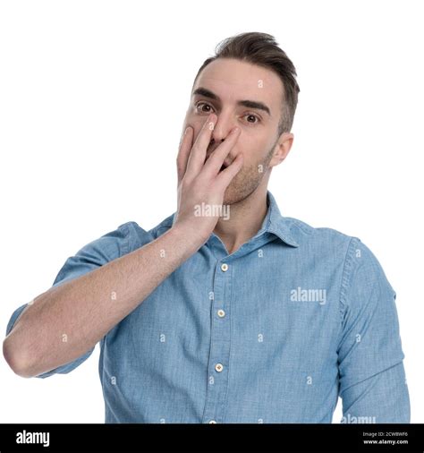 Amazed Casual Man Gasping And Covering His Mouth While Wearing Blue Shirt Standing On White