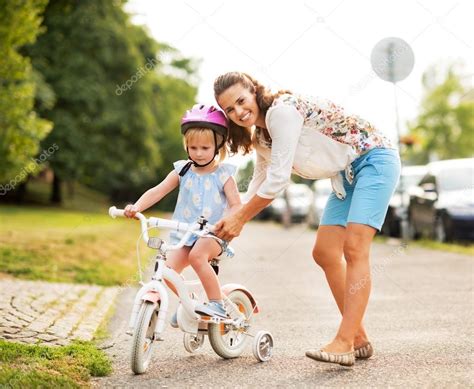 Madre Ayudando A Bebé Niña Montar Bicicleta Fotografía De Stock