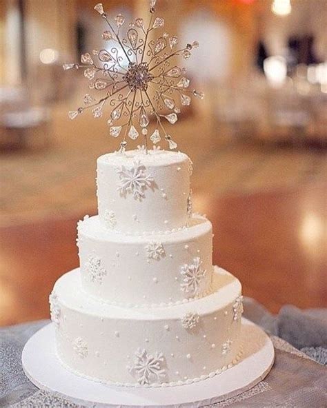 A White Wedding Cake With Snowflakes On Top