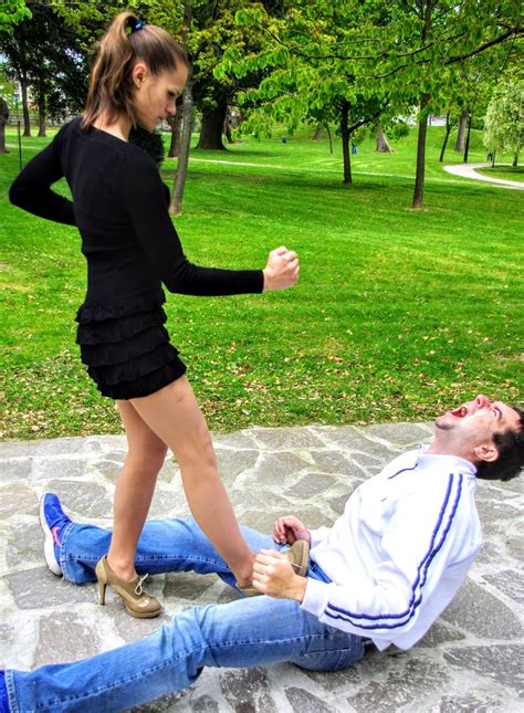 A Man Is Being Dragged By A Woman On The Ground In Front Of Some Trees