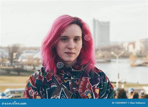 Modern Young Girl With Pink Hair Stands On The Background Of The Urban