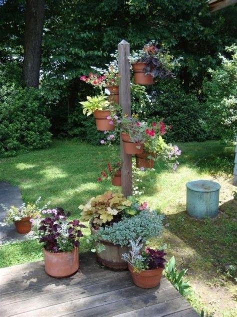 A Wooden Pole With Potted Plants On It In The Middle Of A Garden Area