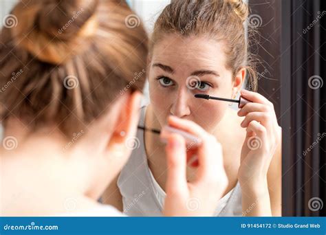 Young Woman Applying Mascara On Her Lower Eyelashes With Mirror Stock