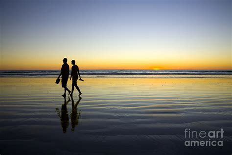 Young Couple Walking On Romantic Beach At Sunset Photograph By Colin
