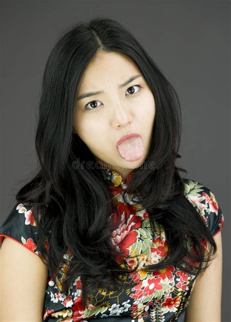 Asian Young Woman Poking Out Tongue Towards Camera On Colored