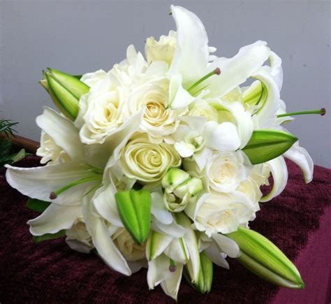 A Bouquet Of White Flowers Sitting On Top Of A Purple Table Cloth Next