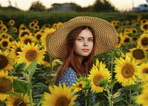 Serious Caucasian Woman Wearing Hat In Field Of Sunflowers Stock