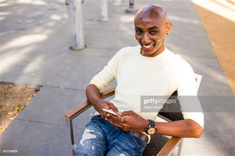 Smiling Gay Black Man Texting In Chair Outdoors Photo Getty Images