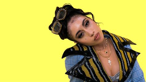 Kali Uchis Is Wearing Colorful Dress Standing In Yellow Wall Background