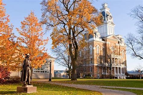 A Statue In Front Of A Tall Building With A Clock Tower