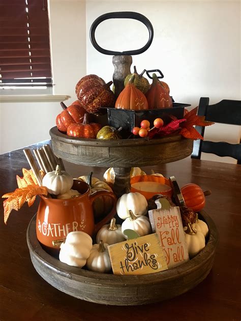 Two Tiered Trays Filled With Pumpkins And Gourds On Top Of A Wooden Table