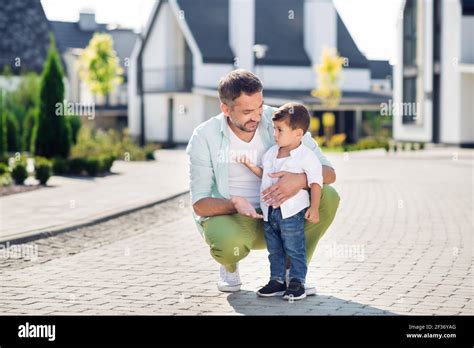 full size photo of father and son on street speak talk communicate conversation dad sits